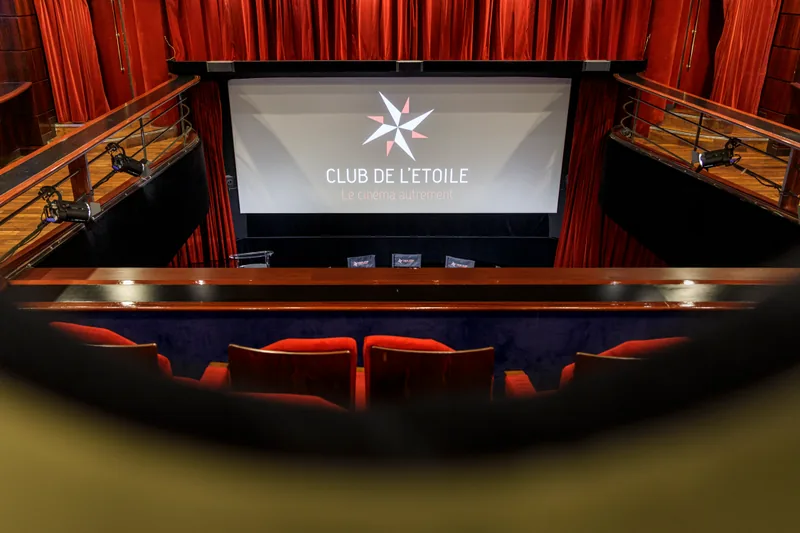 L'écran vu du fond de la salle, par-dessus la rambarde du balcon