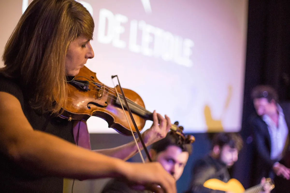 A violinist performing in front of the screen